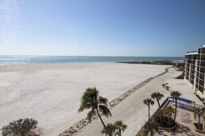 A beach view from a hotel balcony with palm trees and a clear sky. - Luxury Fort Myers Beach Penthouse - Stunning Beachfront View & Pool (Fort Myers Beach)