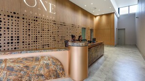 A reception area with a wooden wall, a marble counter, and a sign that reads "ONE ROSEBANK". - Luxe City Vibes in Rosebank (Johannesburg)