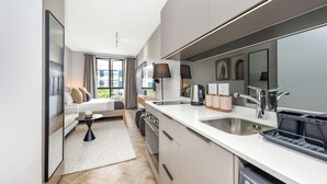 A modern kitchen with a large island, built-in oven, and a dishwasher. There is a seating area with a sofa and a coffee table. - Luxe City Vibes in Rosebank (Johannesburg)