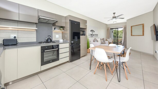 A modern kitchen with a dining area, featuring a built-in oven, microwave, and stainless steel appliances. - Effortless Luxury Living at The View (Sandton)