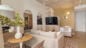 A modern living room with a sofa, a dining table with a vase, and a mirror. - Central Sea Point Studio | Rooftop Pool (Cape Town)