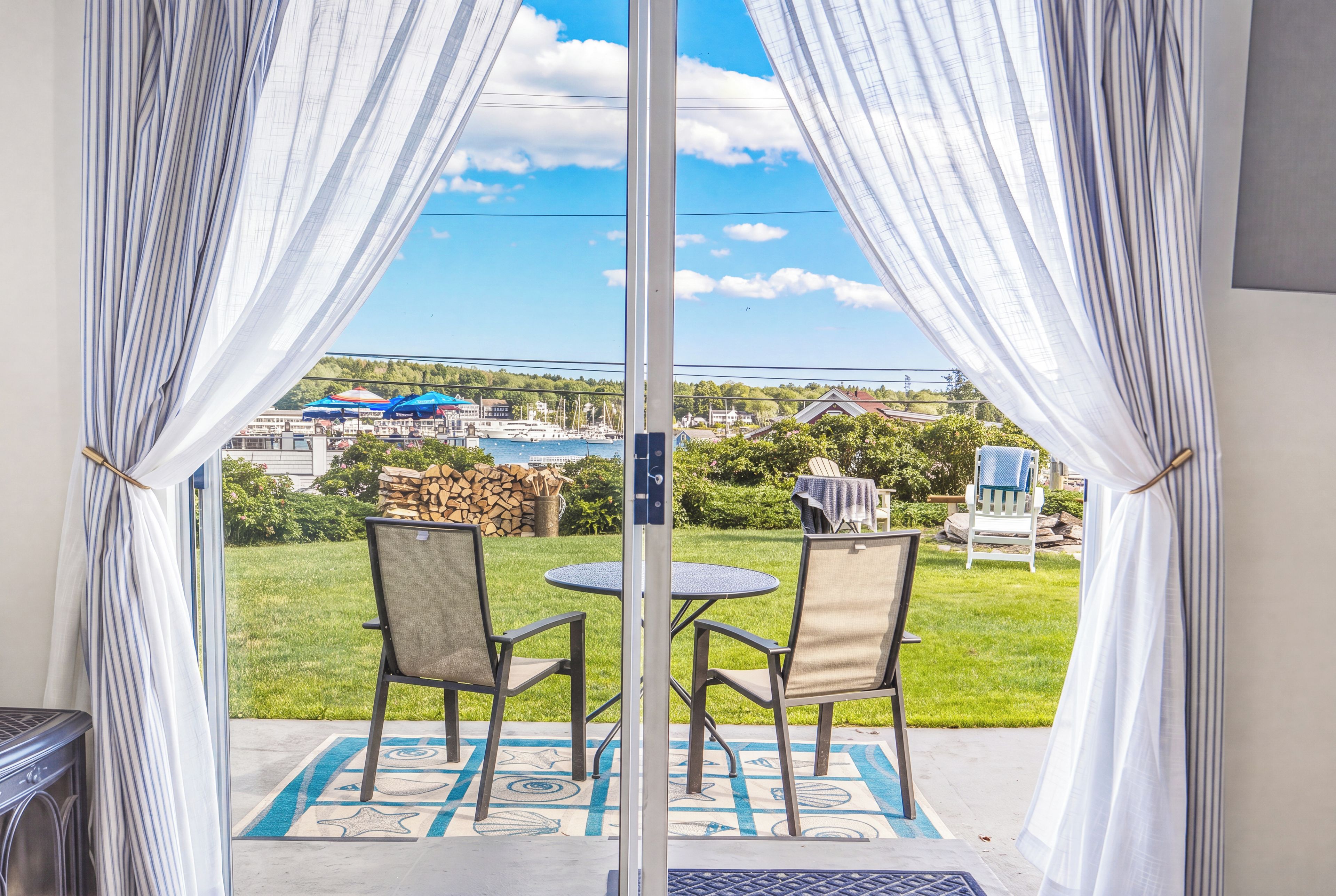 A view from a room with a glass door leading to an outdoor patio with two chairs and a table.