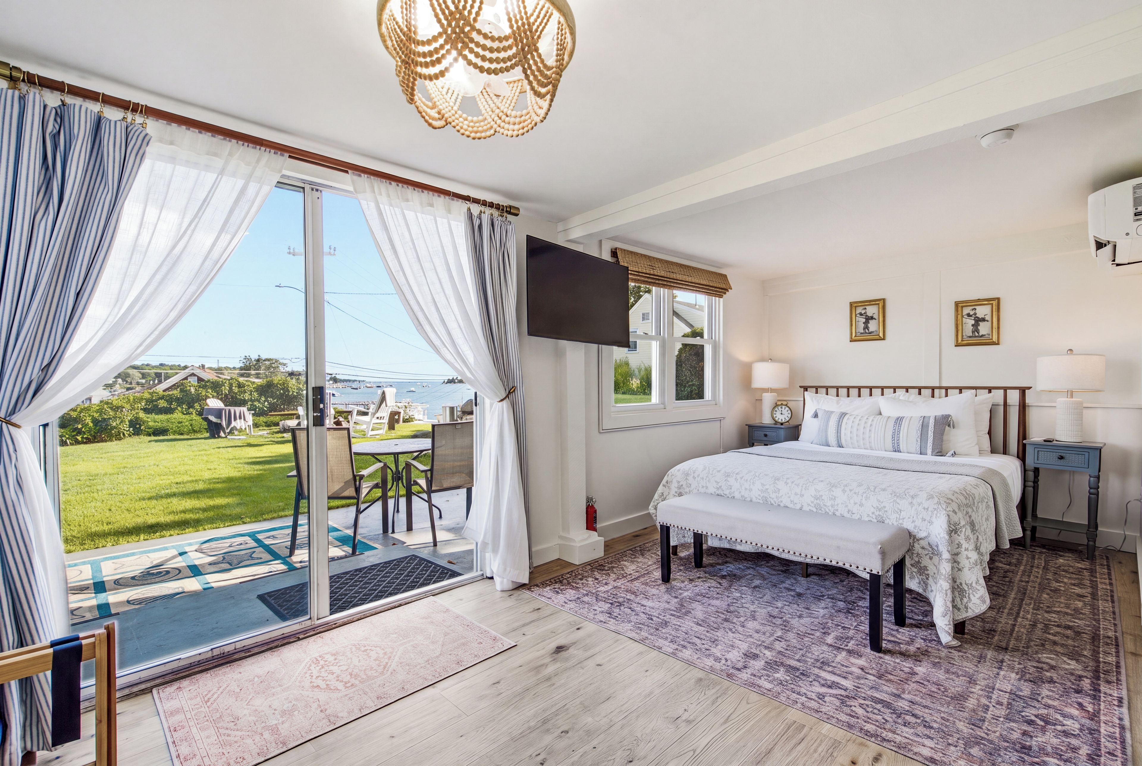 A bedroom with a bed, a TV, and a view of the outdoors.