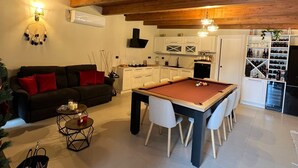 A cozy living room with a pool table, a sofa with red cushions, and a dining area with white chairs. - A beautiful guesthouse where you can relax and enjoy some quality time. (Lanzara)