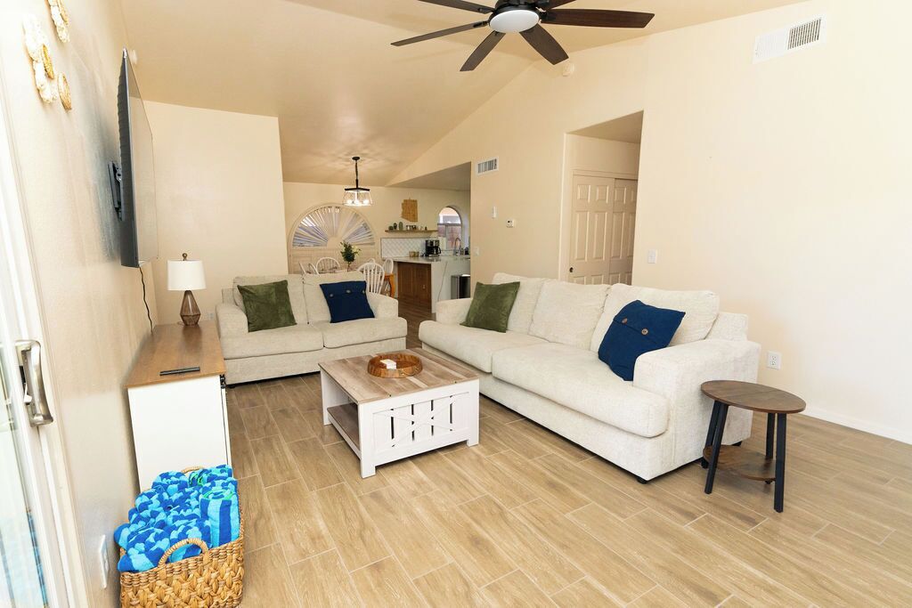 A living room with a white sofa, a wooden coffee table, and a small side table.