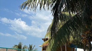 Una piscina con agua azul cristalina, rodeada de palmeras y un edificio con techo de paja.