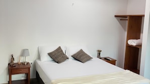 Un dormitorio con cama, mesita de noche, l ámpara y ventilador de techo.
