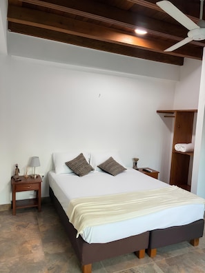 A bedroom with a bed, nightstand, lamp, and a ceiling fan.