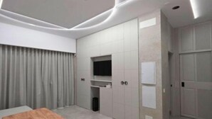 A modern room with a wooden table, a TV mounted on the wall, and built-in wardrobes. - Lux Apartment - Comfort and Charm in the Heart of Palma del Río (Palma del Río)