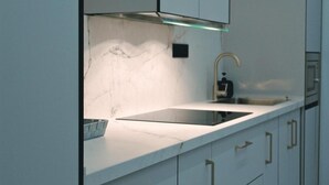 A modern kitchen with a sleek countertop, a stainless steel range hood, and a single faucet. - Lux Apartment - Comfort and Charm in the Heart of Palma del Río (Palma del Río)
