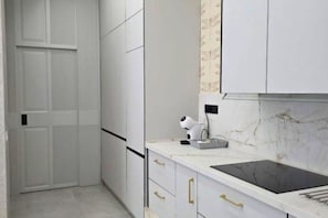 A modern kitchen with white cabinetry, a black countertop, and a marble backsplash. - Lux Apartment - Comfort and Charm in the Heart of Palma del Río (Palma del Río)