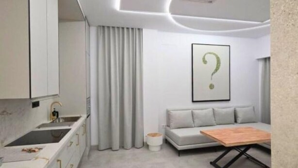 A modern kitchen with a built-in sink, a dining area with a wooden table, and a grey sofa. - Lux Apartment - Comfort and Charm in the Heart of Palma del Río (Palma del Río)