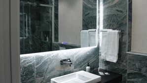 A modern bathroom with a large mirror, marble walls, a black countertop, and a white sink. - Lux Apartment - Comfort and Charm in the Heart of Palma del Río (Palma del Río)