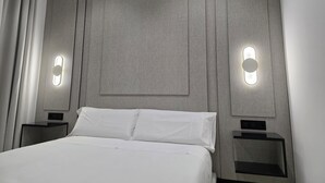 A modern hotel room with a large bed, two bedside tables, and wall-mounted lighting. - Lux Apartment - Comfort and Charm in the Heart of Palma del Río (Palma del Río)