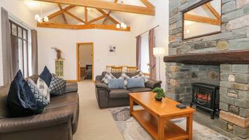 A cozy living room with a stone fireplace, leather sofas, and a wooden ceiling.