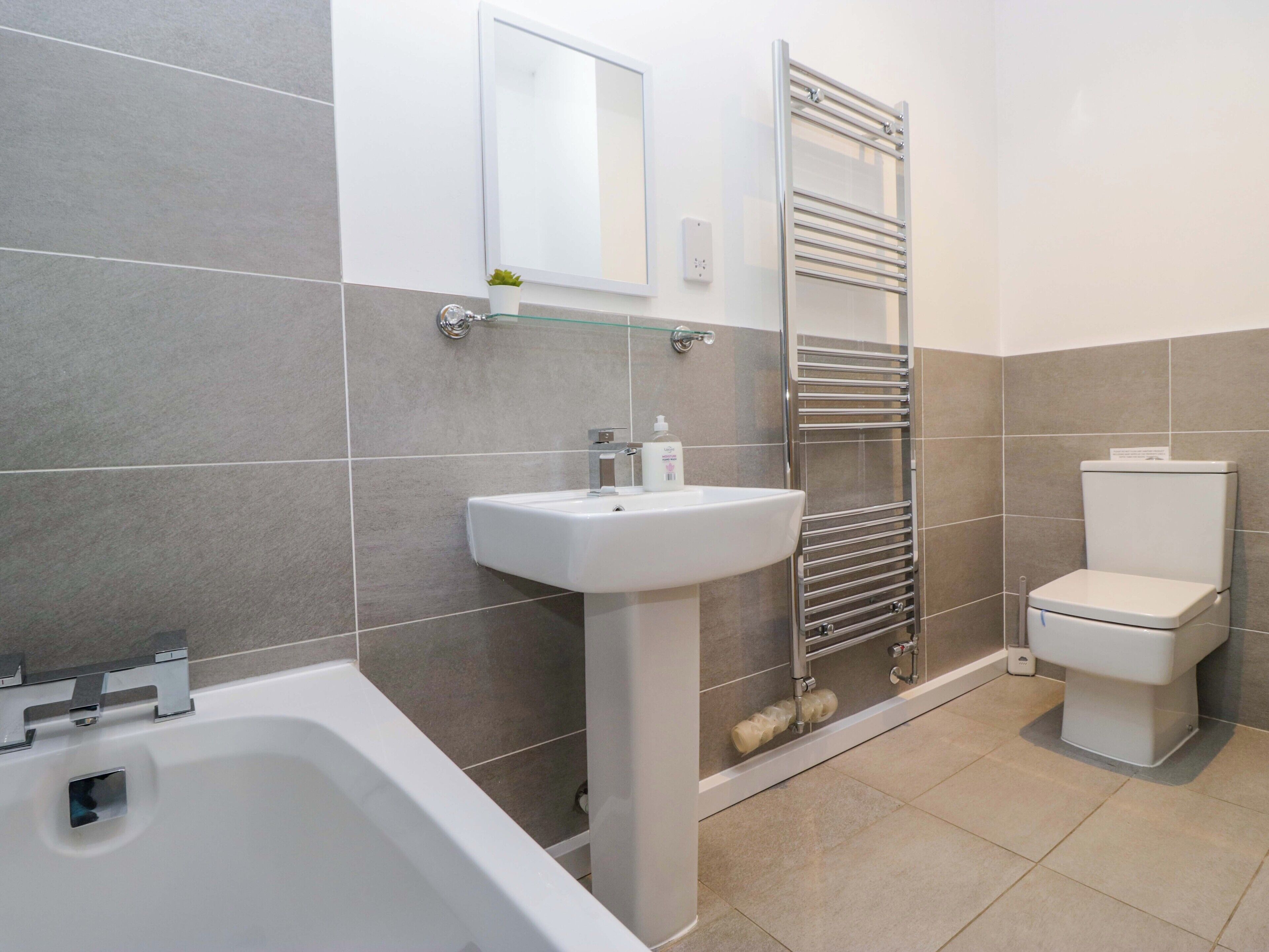 A modern bathroom with a bathtub, sink, and toilet.