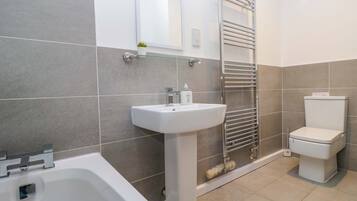 A modern bathroom with a bathtub, sink, and toilet.