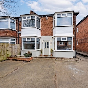 A two-story residential building with a bay window on the ground floor and a dormer window on the upper floor.