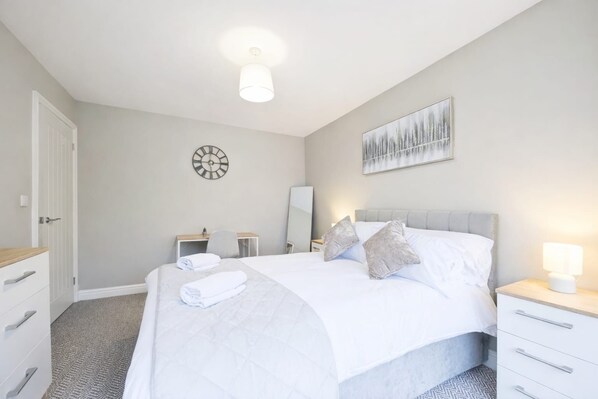A modern bedroom with a bed, bedside tables, a desk, and a clock on the wall. - 2 Bed Flat, Newcastle, 5 min to City, Free parking - Pass the Keys (Newcastle)