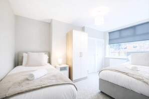 A modern hotel room with two beds, a wardrobe, and a window with a view. - 2 Bed Flat, Newcastle, 5 min to City, Free parking - Pass the Keys (Newcastle)