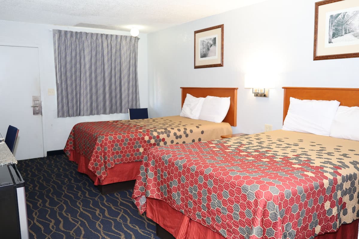 A hotel room with two beds, a desk, and a chair.