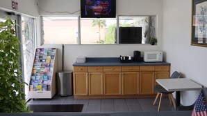 A small kitchenette with a microwave, a sink, and a window with a view of the outside.