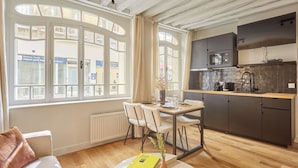 A modern kitchen with a dining area, large windows, and a view of the street. - Superb AC Apartement Notre Dame de Paris (Paris)