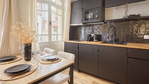 A modern kitchen with dark cabinets, a microwave, and a tiled backsplash. - Superb AC Apartement Notre Dame de Paris (Paris)