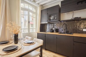 A modern kitchen with dark cabinets, a microwave, and a tiled backsplash. - Superb AC Apartement Notre Dame de Paris (Paris)