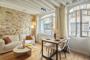 Un salon chaleureux avec un mur en pierre, une table à manger en bois et un canapé.