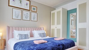Une chambre à coucher comprenant un lit, des tables de chevet, une armoire et des œuvres d’art encadrées accrochées au mur.