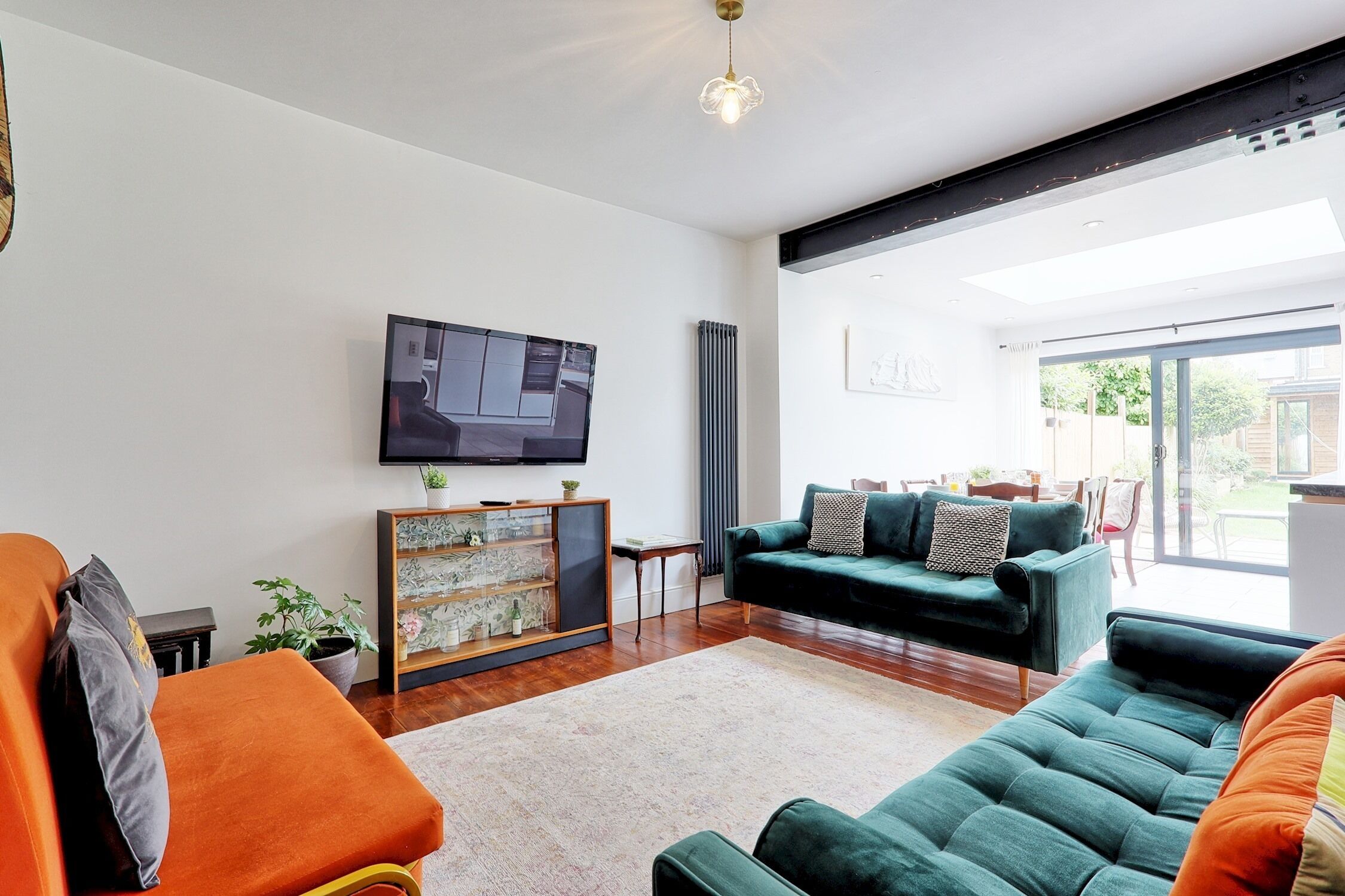Un salon moderne avec un téléviseur à écran plat, un canapé vert et un fauteuil orange.