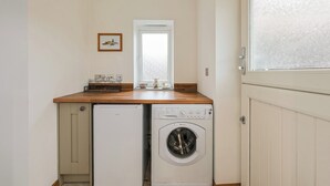 Ein kleiner Waschbereich mit einer Waschmaschine und einem Kühlschrank.