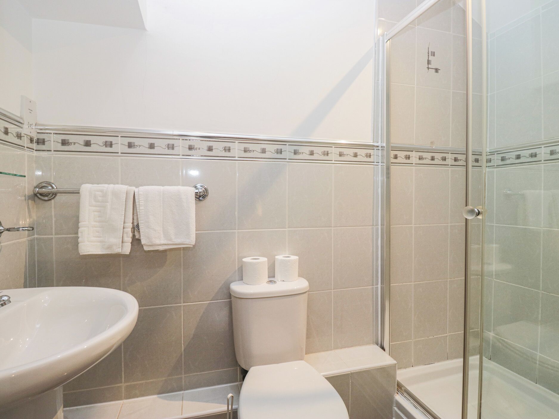 A modern bathroom with a glass shower enclosure, a white sink, and a toilet.