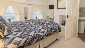 A bedroom with a bed, a desk, a mirror, and a bathroom. - Newlands Fell House (Keswick)