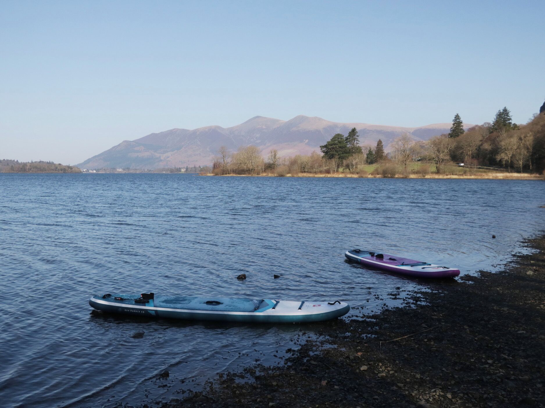Deux kayaks sur un lac paisible, avec des montagnes en arrière-plan.