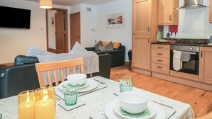 A compact living space with a dining area, kitchenette, and a living room. - Newlands Cottage (Keswick)