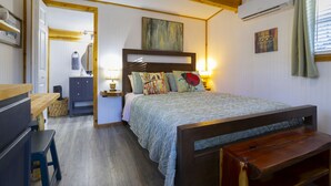 Une chambre à coucher avec un lit, des tables de chevet, une lampe et un banc en bois.