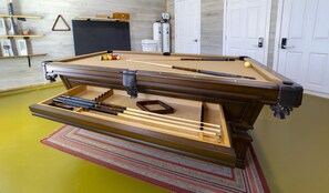 A pool table with a built-in chalk rail and pockets, surrounded by a wooden frame.