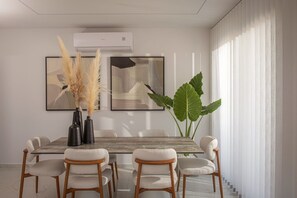 A dining area with a wooden table, six chairs, two vases with pampas grass, and a large plant. - Villa Sol: Luxury Living in Heart of Gournes (Gournes Gouvon)