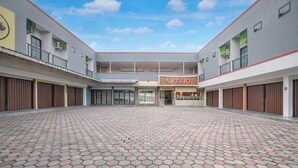 A courtyard with a hexagonal tiled floor, a central entrance, and a store named 'TRIO' on the right.