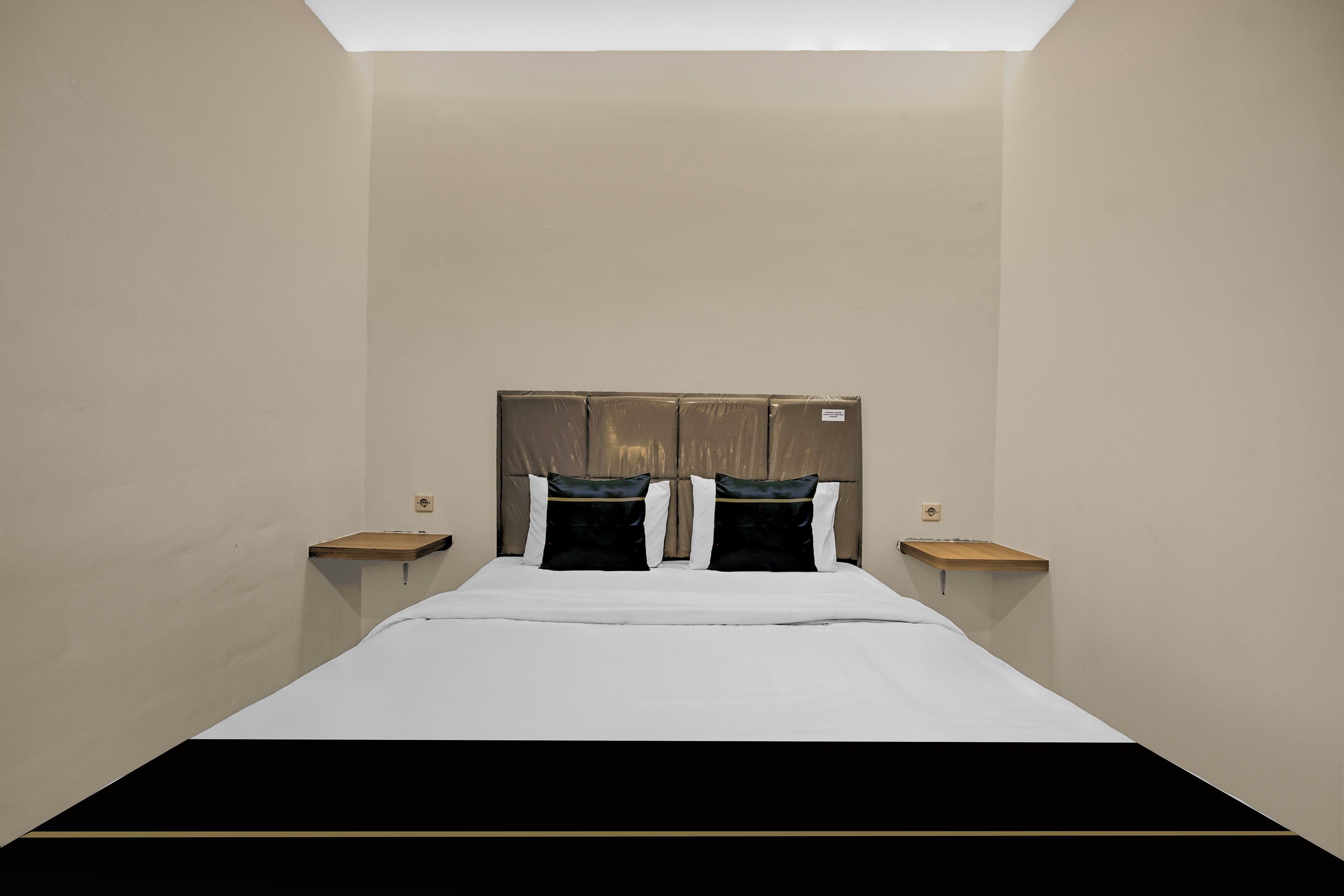 Una habitación con cama, dos mesitas de noche, cabecera y tragaluz.