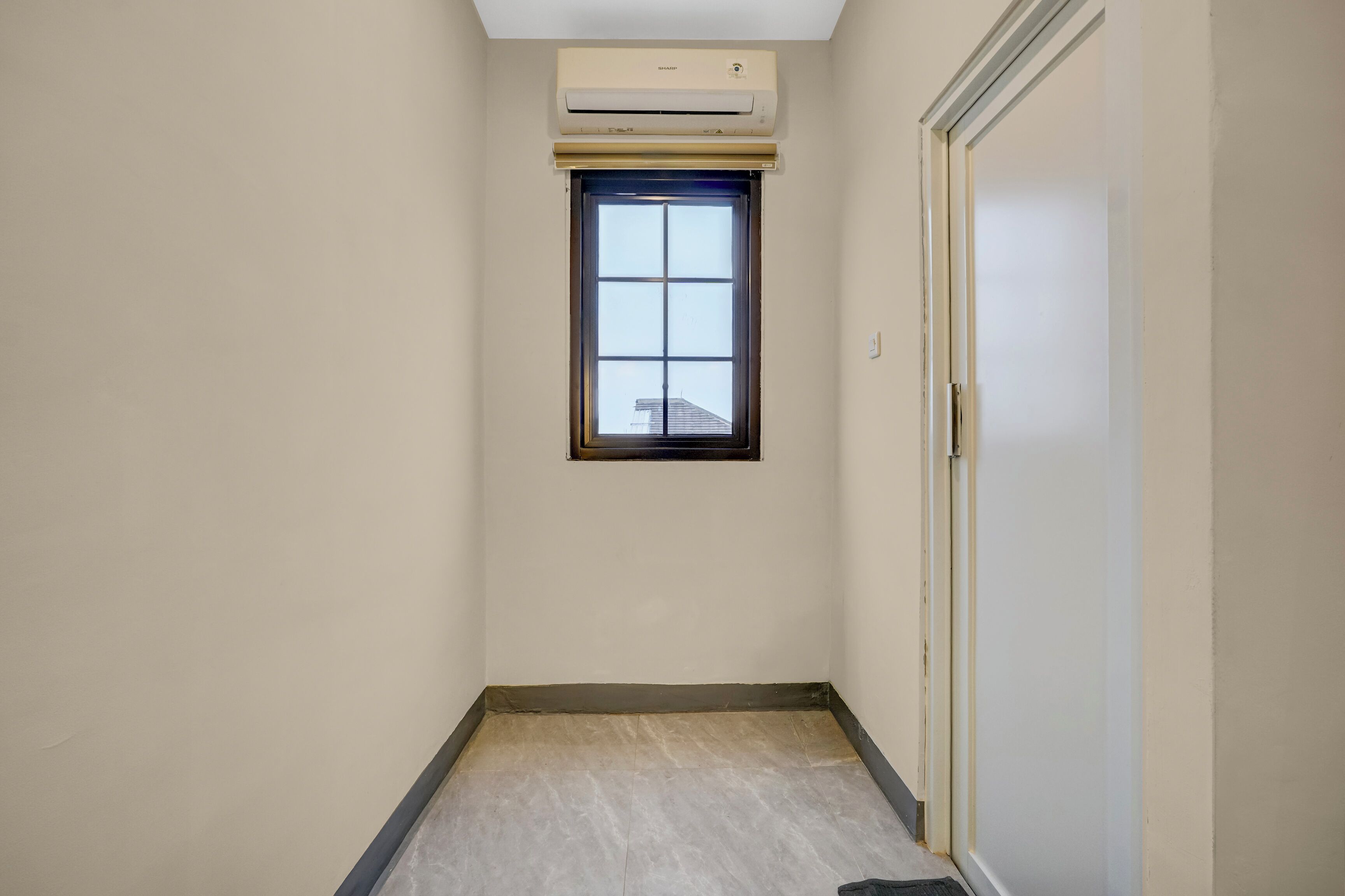 A narrow hallway with a window, a door, and an air conditioning unit.