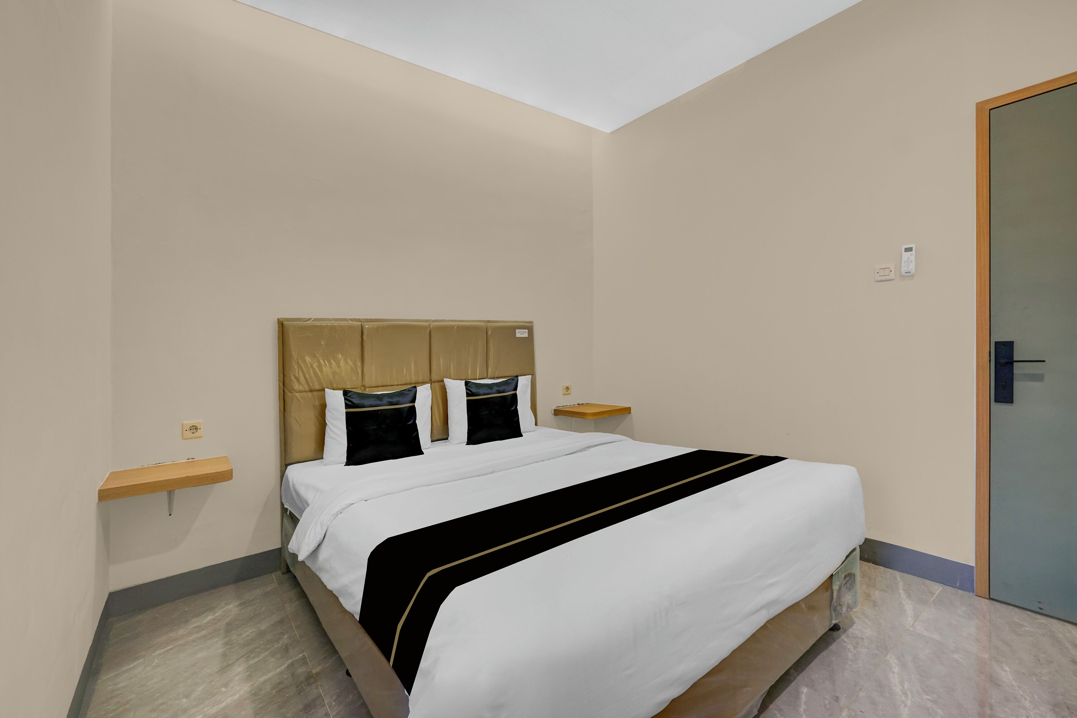 A neatly arranged hotel room with a bed, bedside tables, a nightstand, and a door.