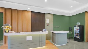 A reception area with a wooden reception desk, a water dispenser, and a small refrigerator.