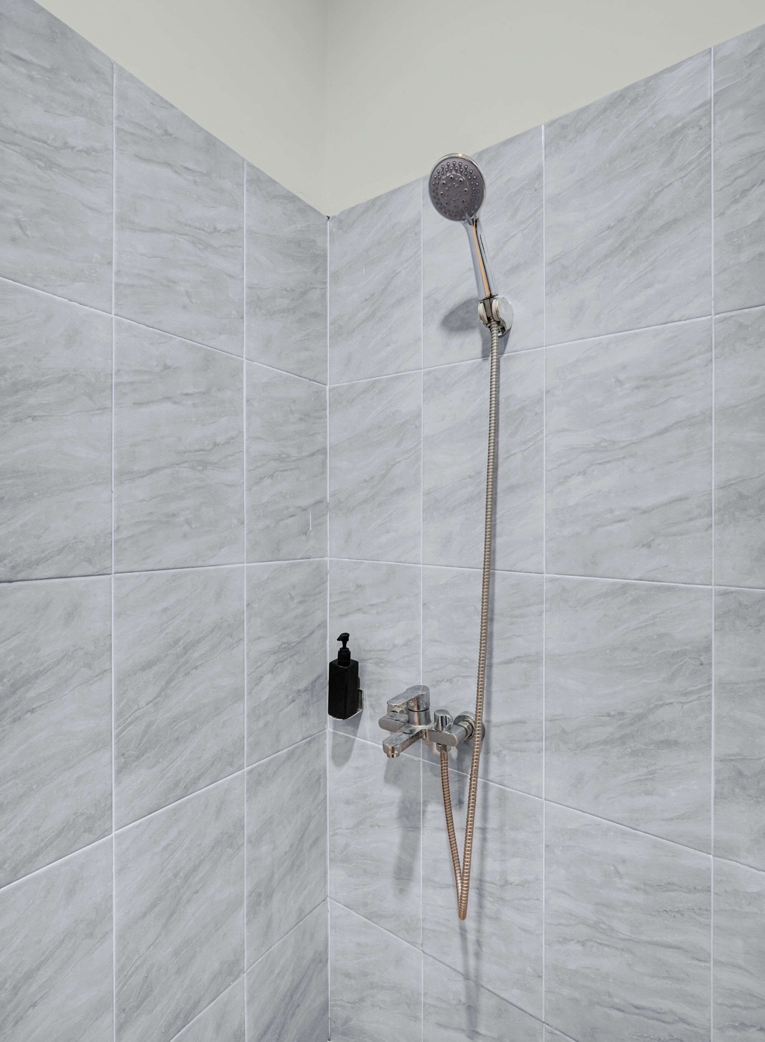 Eine Dusche mit Handbrause und Armaturen an der Wand.
