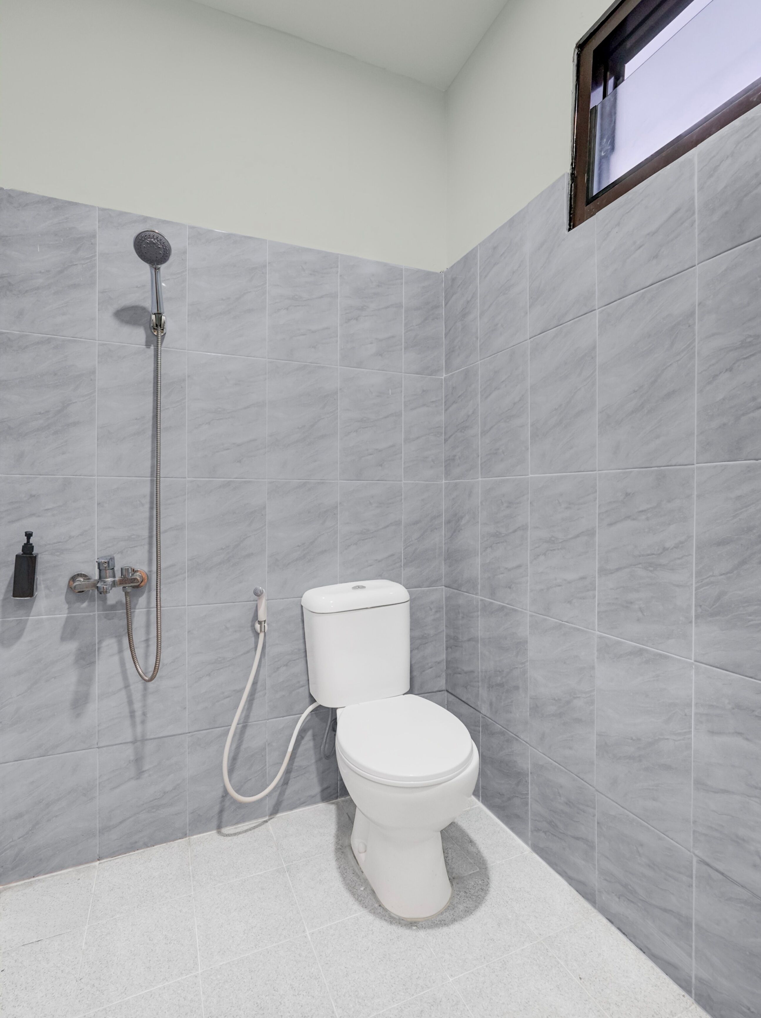 A bathroom with a toilet, a shower, and a window.