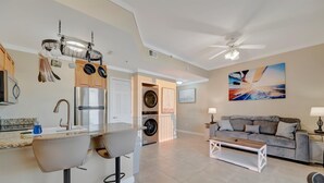 Una cocina moderna con horno empotrado, refrigerador y pileta. Hay una zona de comedor con sofá y mesa baja.