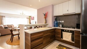Una cocina moderna con una isla central, armarios de madera, horno empotrado y un comedor con sofá y sillas.