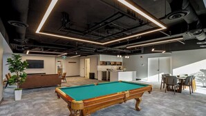 A modern indoor pool table with a green felt surface, surrounded by a grey carpeted area. - Sauna, Gym, Pool Table, Walk to Cafes & Sights (Calgary)